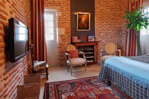 a bedroom with a bed and a tv and a brick wall at Chambres d'hôtes La Tour Sainte-Cécile in Albi