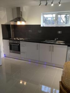a kitchen with white cabinets and a stove top oven at Small Modern Comfortable 2 Bedroom Apartment cmyr in Hayes