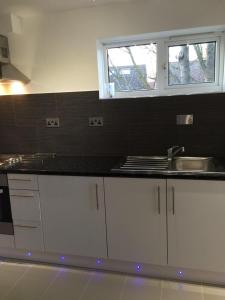 a kitchen with white cabinets and a sink and a window at Small Modern Comfortable 2 Bedroom Apartment cmyr in Hayes