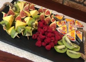 a plate of fruit with raspberries and kiwis at Kliprand Guest House in Springbok