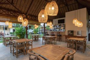 a restaurant with wooden tables and chairs and chandeliers at InBalance Resort in Buleleng