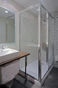 y baño con ducha y lavamanos. en Hostal Carlos III, en Getafe