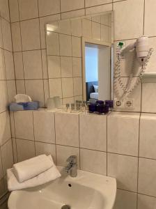 a white bathroom with a sink and a mirror at Hotel Gloria in Alsdorf