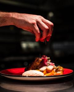 una persona enciende una vela en un plato de comida en Frösö Park Hotel, en Östersund