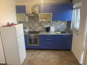 La cuisine est équipée de placards bleus et d'un réfrigérateur blanc. dans l'établissement Bella Vista, à Ankaran