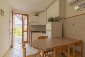una cucina con tavolo, sedie e frigorifero di Casa Vacanze Lentisco by HelloElba a Marina di Campo