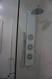 a shower door with a shower head and a sink at Apartament Dwa kroki do zatoki in Puck