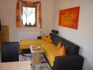 a living room with a yellow couch and a table at Ferienwohnung Wettl in Vorderberg