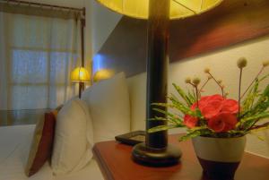 a table with a lamp and a vase with flowers on it at Maekok River Village Resort in Mae Ai