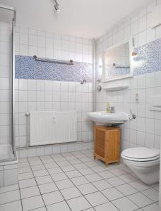 La salle de bains est pourvue de carrelage blanc, de toilettes et d'un lavabo. dans l'établissement Appartements Am Reiterhof Meerzeit, à Timmendorfer Strand