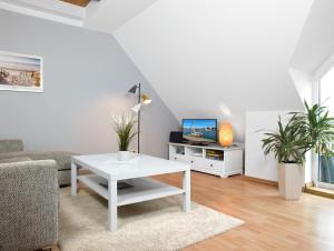 a living room with a white table and a tv at Appartements Am Reiterhof Meerzeit in Timmendorf