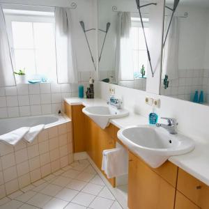 a bathroom with two sinks and a tub and a mirror at Ferienwohnung Riesenblick in Frasdorf