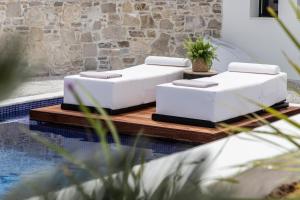 twee witte stoelen op een tafel naast een zwembad bij The Sand Suites - Adults Only in Agios Nikolaos