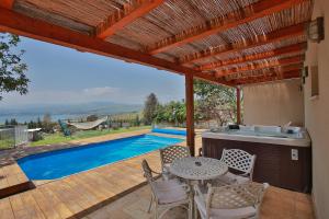 um pátio com uma mesa e cadeiras e uma piscina em The White Chalet Boutique em Moshav Ramot