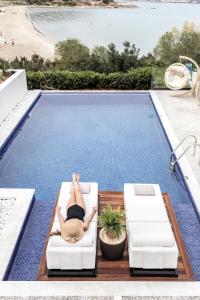 a woman laying on a chair next to a swimming pool at The Sand Suites - Adults Only in Agios Nikolaos