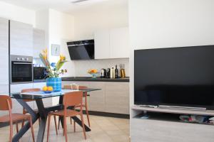 a kitchen with a table and a large television at Casa Mari in Villasimius