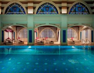 迪拜Jumeirah Zabeel Saray Dubai的酒店里的游泳池，配有桌椅