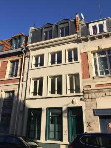 - un bâtiment blanc avec des portes et des fenêtres vertes dans l'établissement Le Chat Qui Dort, à Lille