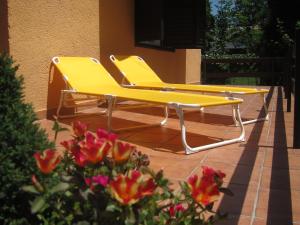 dos sillas amarillas sentadas en un patio con flores en Tutijó Házikó en Balatonfenyves