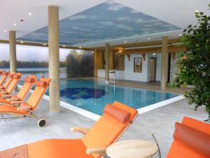 a swimming pool with orange chairs and a table at Chalets am Rößle in Todtmoos