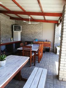 an outdoor patio with wooden tables and chairs at Voni's Cottage in Vredendal