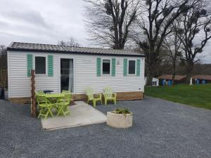 a white house with green chairs and a patio at Puy Rond Camping in Bressuire