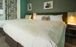 a bed with a white comforter and pillows at Caring Hotel in London