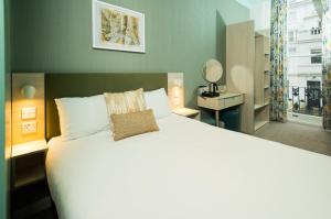 Un dormitorio con una cama grande con una almohada. en Caring Hotel en Londres