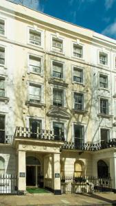 a large white building with a fence in front of it at Caring Hotel in London