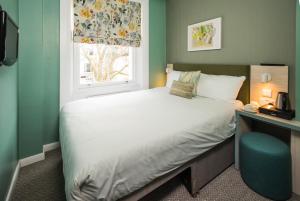 Un dormitorio con una cama grande y una ventana en Caring Hotel en Londres