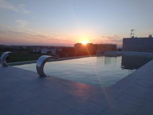 a pool on top of a building with the sunset at Salina Hotel in Taranto