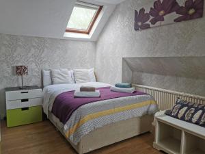 um quarto com uma cama com lençóis roxos e uma janela em Adams Guest House em Oxford