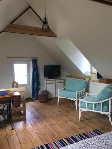 Cette chambre mansardée comprend deux chaises et une télévision. dans l'établissement La maison du pêcheur, à Saint-Quay-Portrieux