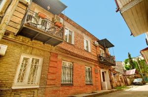 ein altes Backsteingebäude mit Balkon auf einer Straße in der Unterkunft Old Tbilisi Gate in Tbilisi City