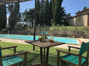 a table and two chairs next to a swimming pool at Villa di Montegemoli in Pomarance