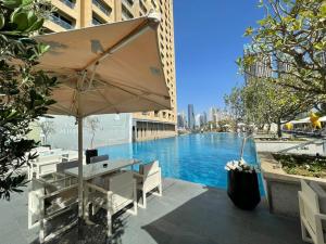 Ultimate Luxury at Fashion Avenue Dubai Mall Residences في دبي: طاولة مع مظلة بجانب مسبح