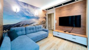 a living room with a blue couch and a flat screen tv at Apartamenty EverySky Nad Łomnicą 15-15A in Karpacz