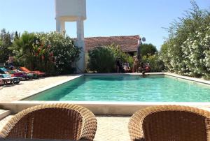a swimming pool with two wicker chairs in front of it at Casas e Glamping Quinta da Saudade in Canha