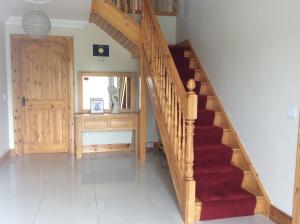 - un escalier dans une maison dotée d'un tapis rouge dans l'établissement Ardaobhainn, à Letterkenny