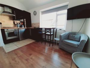 een keuken en een woonkamer met een bank en een stoel bij Cosy 1 Bedroom Apartment in the Heart of Llandudno in Llandudno