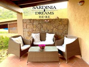 un patio con sillas de mimbre y una mesa con un cartel en Villa Flavia con piscina en Costa Paradiso