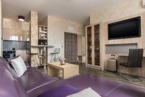 Una sala de estar con un sofá morado y un televisor. en Boutique Apartments - Sevtopolis, en Kazanlak