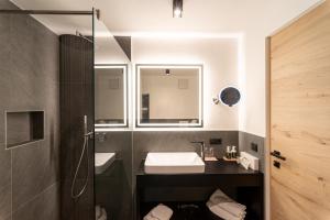 y baño con lavabo y ducha. en Penserhof - Alpine Hotel & Restaurant en Sarntal