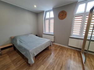 1 dormitorio con 1 cama y reloj en la pared en Ines Apartament en Ostrów Wielkopolski
