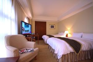 um quarto de hotel com duas camas e uma televisão de ecrã plano em Grand Boss Hotel em Yilan City