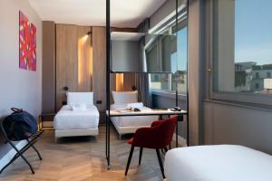 
a room with a bed, chair, table and a television at B&B Hotel Milano City Center Duomo in Milan
