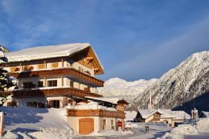 ein schneebedecktes Gebäude mit Bergen im Hintergrund in der Unterkunft Penserhof - Alpine Hotel & Restaurant in Sarntal