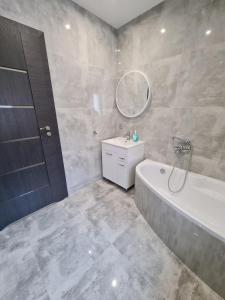 y baño con bañera, lavabo y espejo. en Ines Apartament en Ostrów Wielkopolski