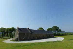 GuerlédanにあるLE HERON - LES VERGERS DE GUERLEDANの野原の道沿いにある古いレンガ造りの納屋