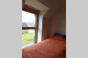 GuerlédanにあるLE HERON - LES VERGERS DE GUERLEDANのベッドと窓のある寝室